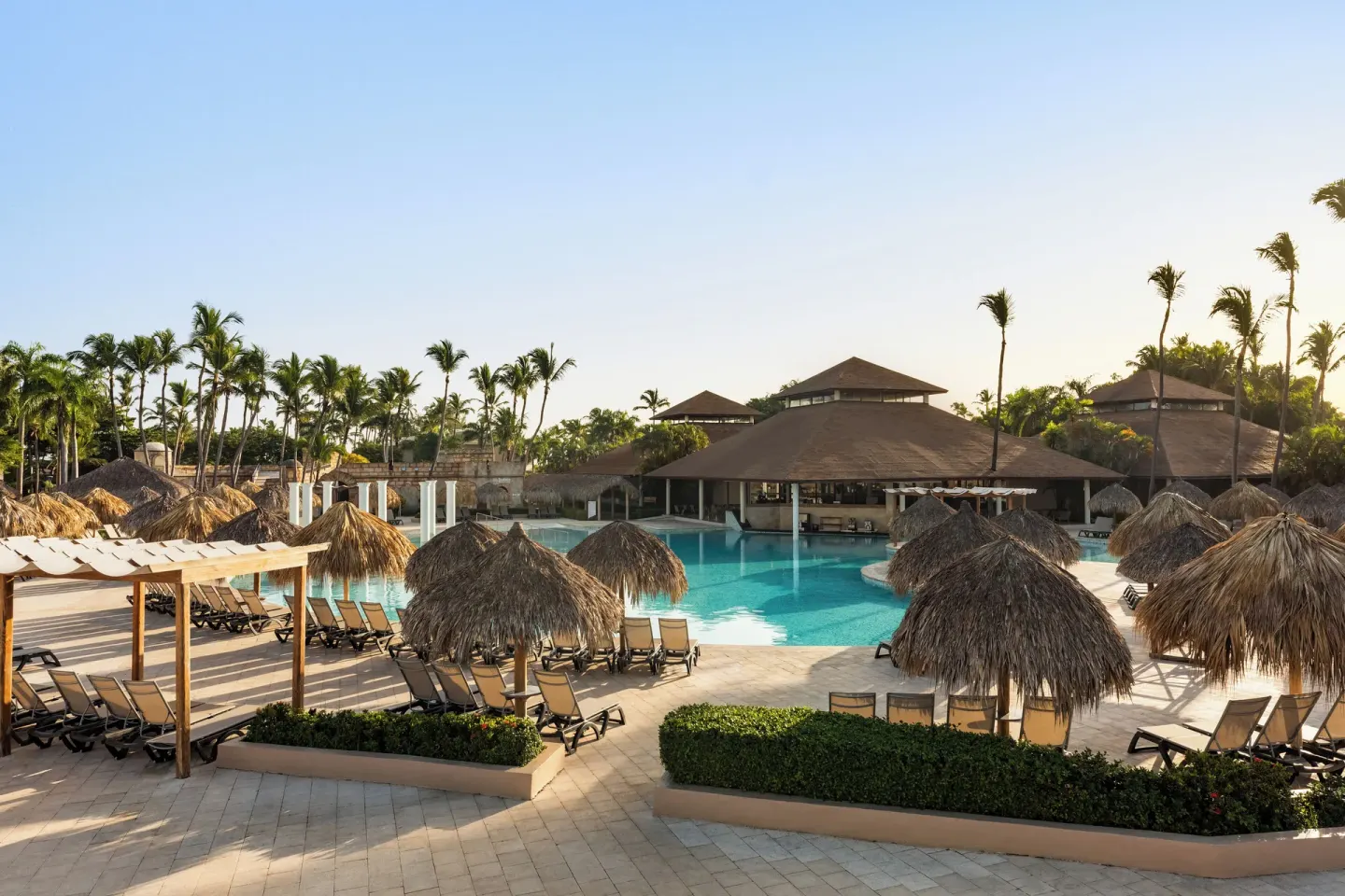 Pool area with palapa umbrellas and loungers at Grand Palladium Punta Cana Resort & Spa.