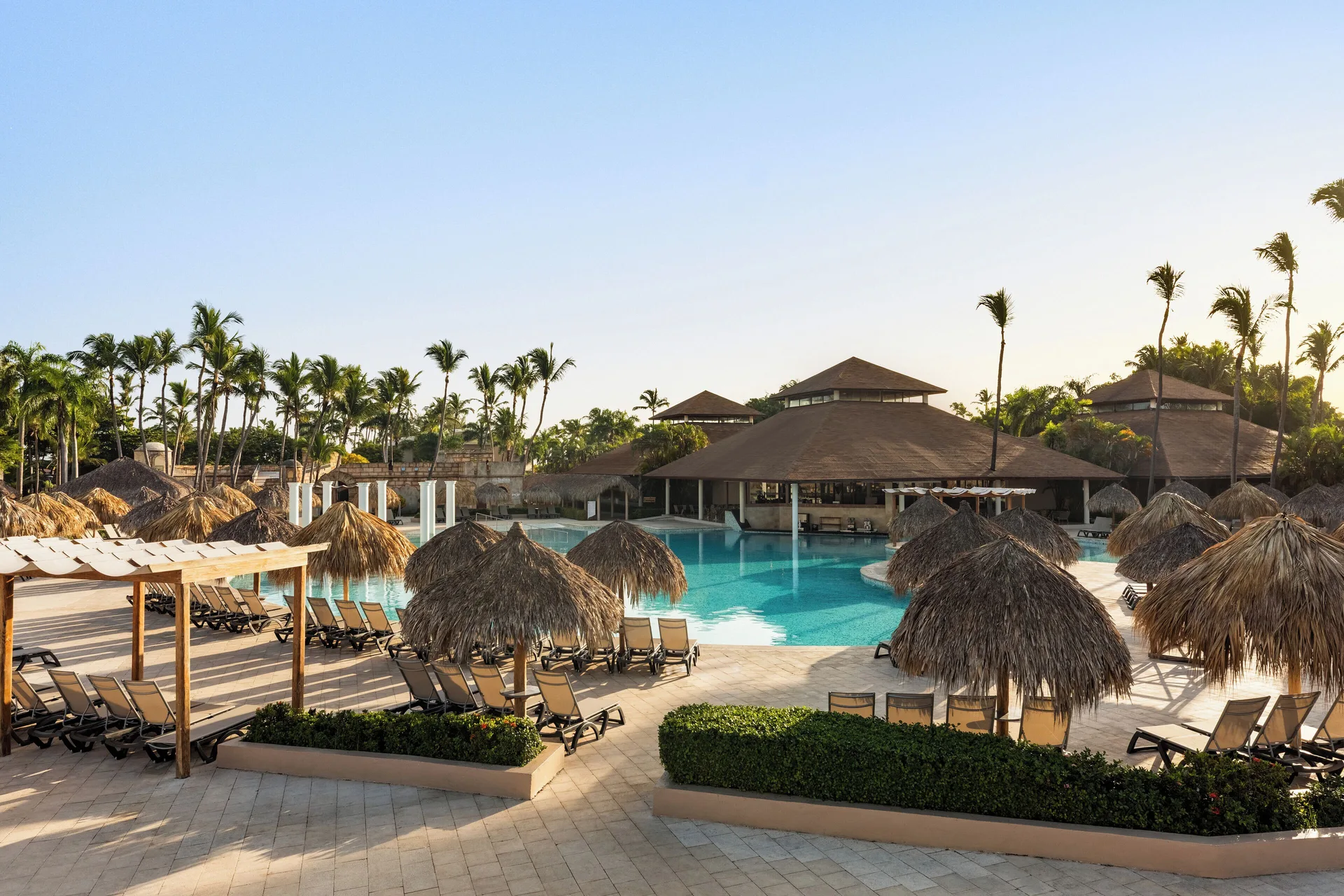 Pool area with palapa umbrellas and loungers at Grand Palladium Punta Cana Resort & Spa.