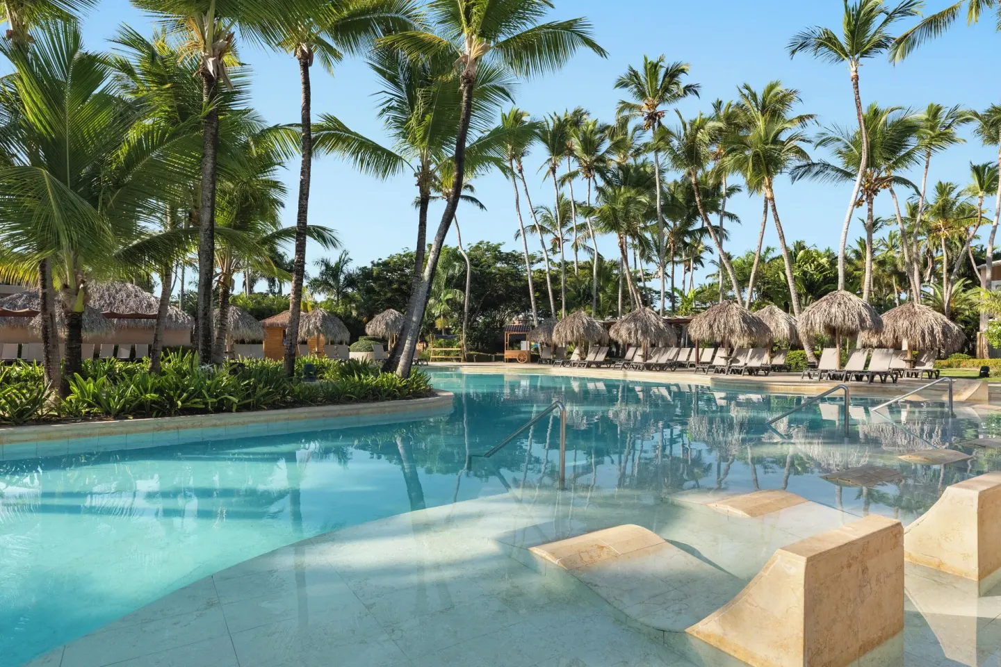 Palm-lined pool with submerged loungers at Grand Palladium Punta Cana Resort & Spa.
