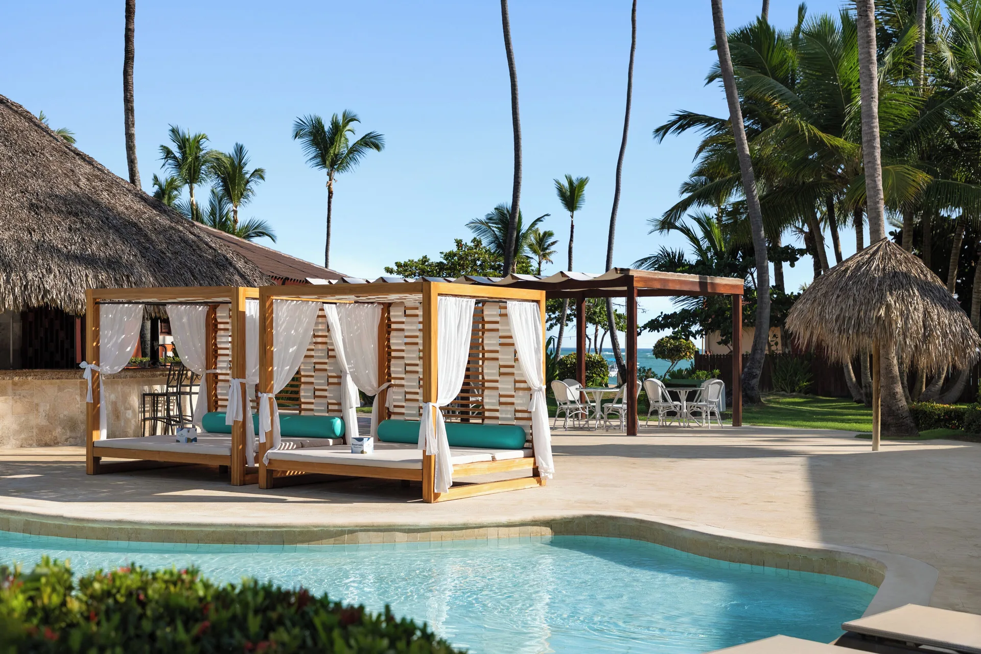 Poolside cabana beds with white curtains at Grand Palladium Punta Cana Resort & Spa.