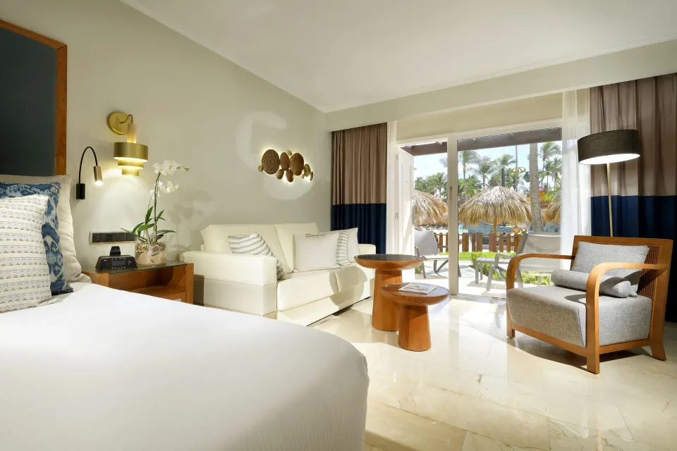 Junior Suite Poolside king bed, sofa, and terrace doors at Grand Palladium Punta Cana Resort & Spa.