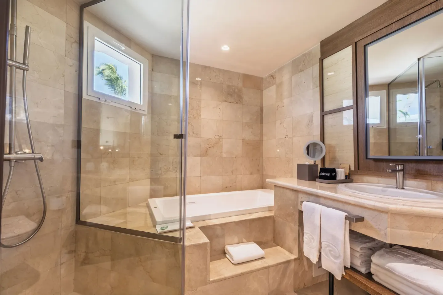 Bathroom with glass shower, raised soaking tub, and vanity at Grand Palladium Select Bávaro.