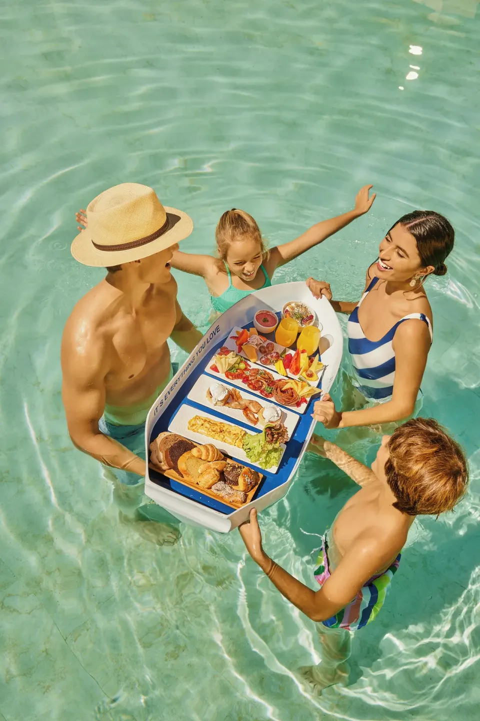 Family enjoying a floating breakfast tray in the pool at Grand Palladium Select Bávaro.