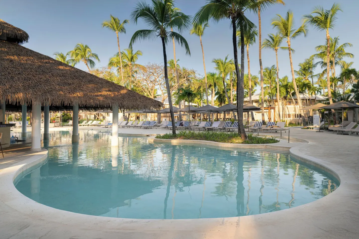 Lagoon-style pool with palm trees and loungers at Grand Palladium Select Bávaro.