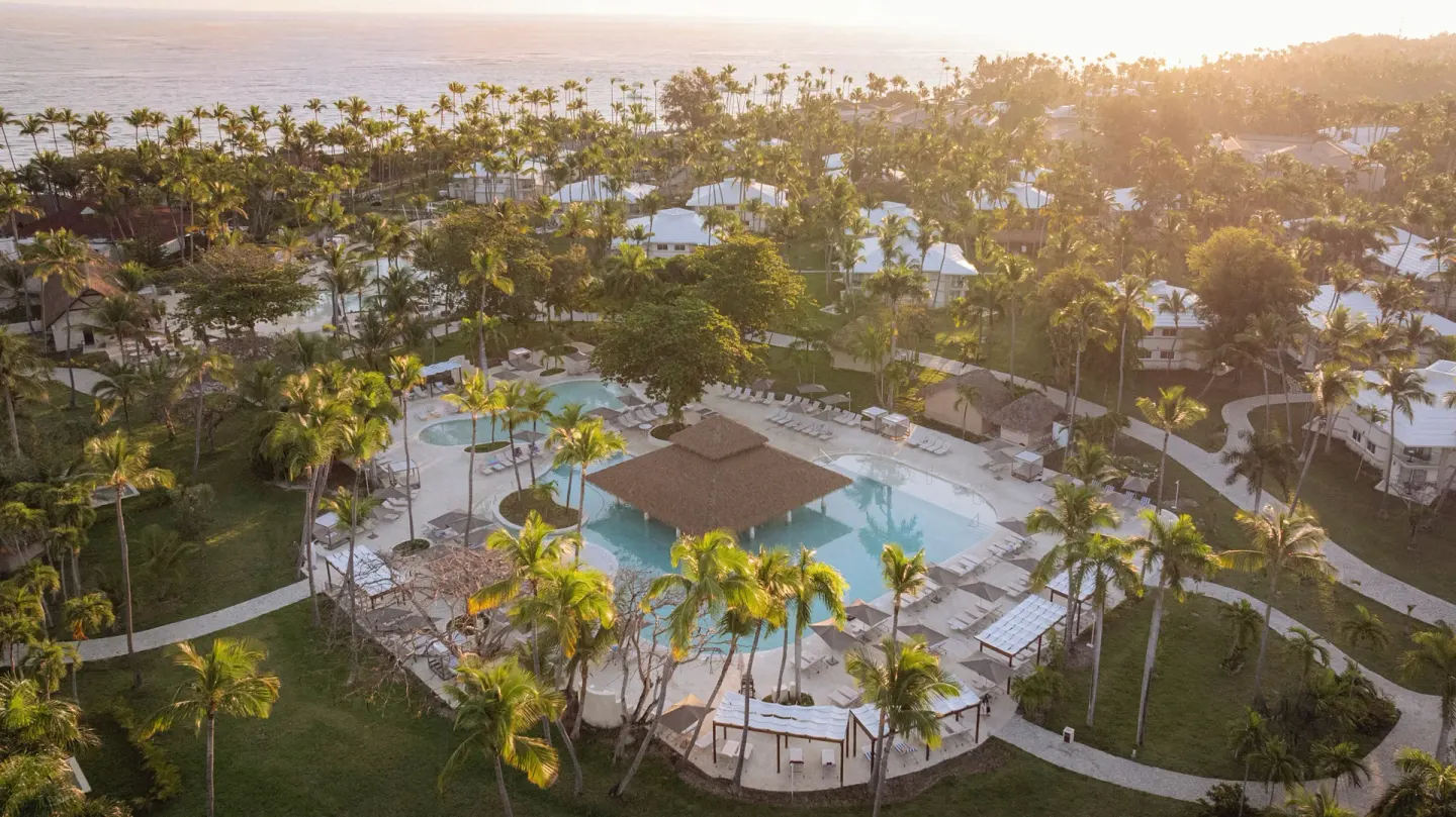 Sunset aerial view of the resort pool and palm gardens at Grand Palladium Select Bávaro.