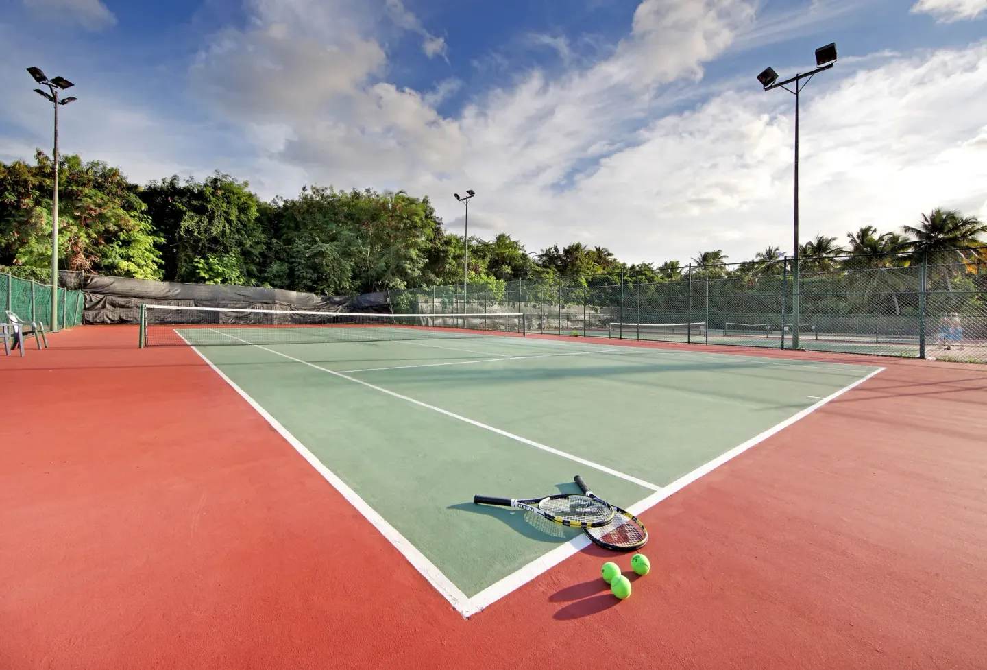 Tennis court with rackets and balls in the corner at Grand Palladium Select Bávaro.