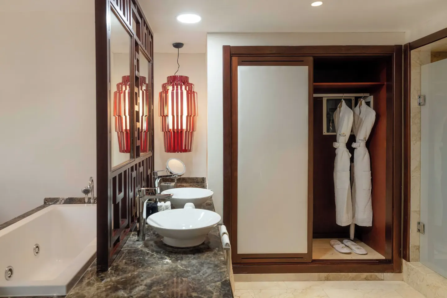 Junior Suite Beachside bathroom with tub, double sinks, and robes at Grand Palladium Select Bávaro.