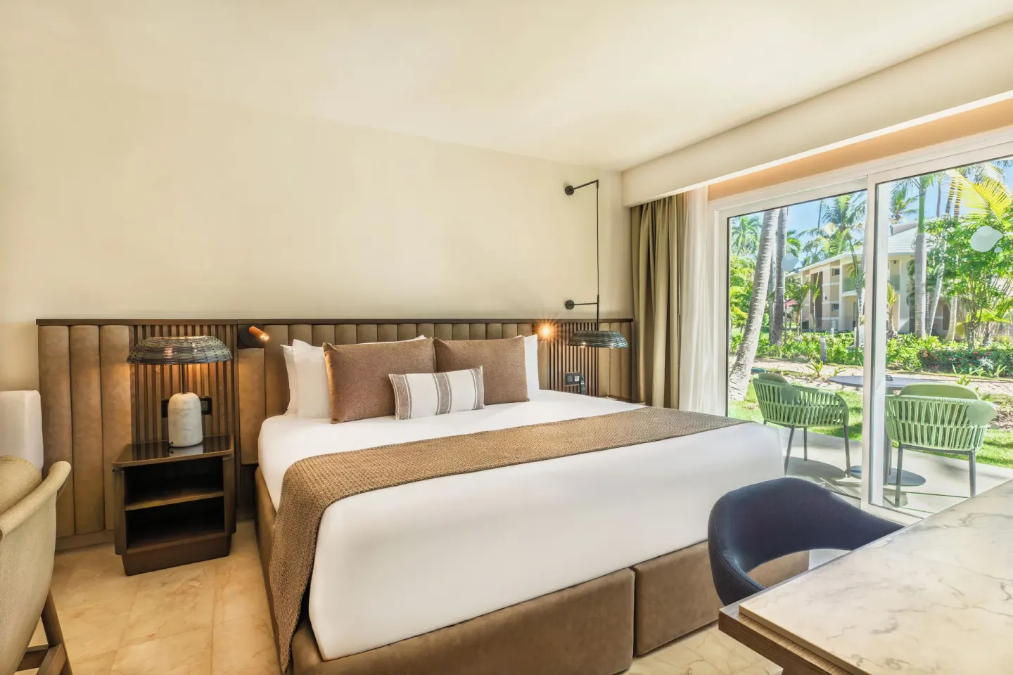 Junior Suite Garden View king bed beside patio doors at Grand Palladium Select Bávaro.