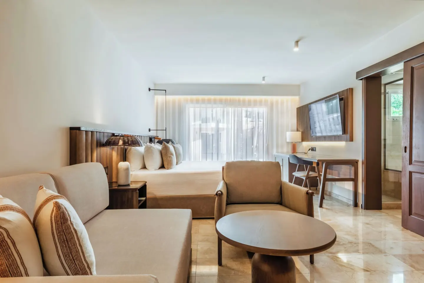 Junior Suite Garden View seating area and bed at Grand Palladium Select Bávaro.