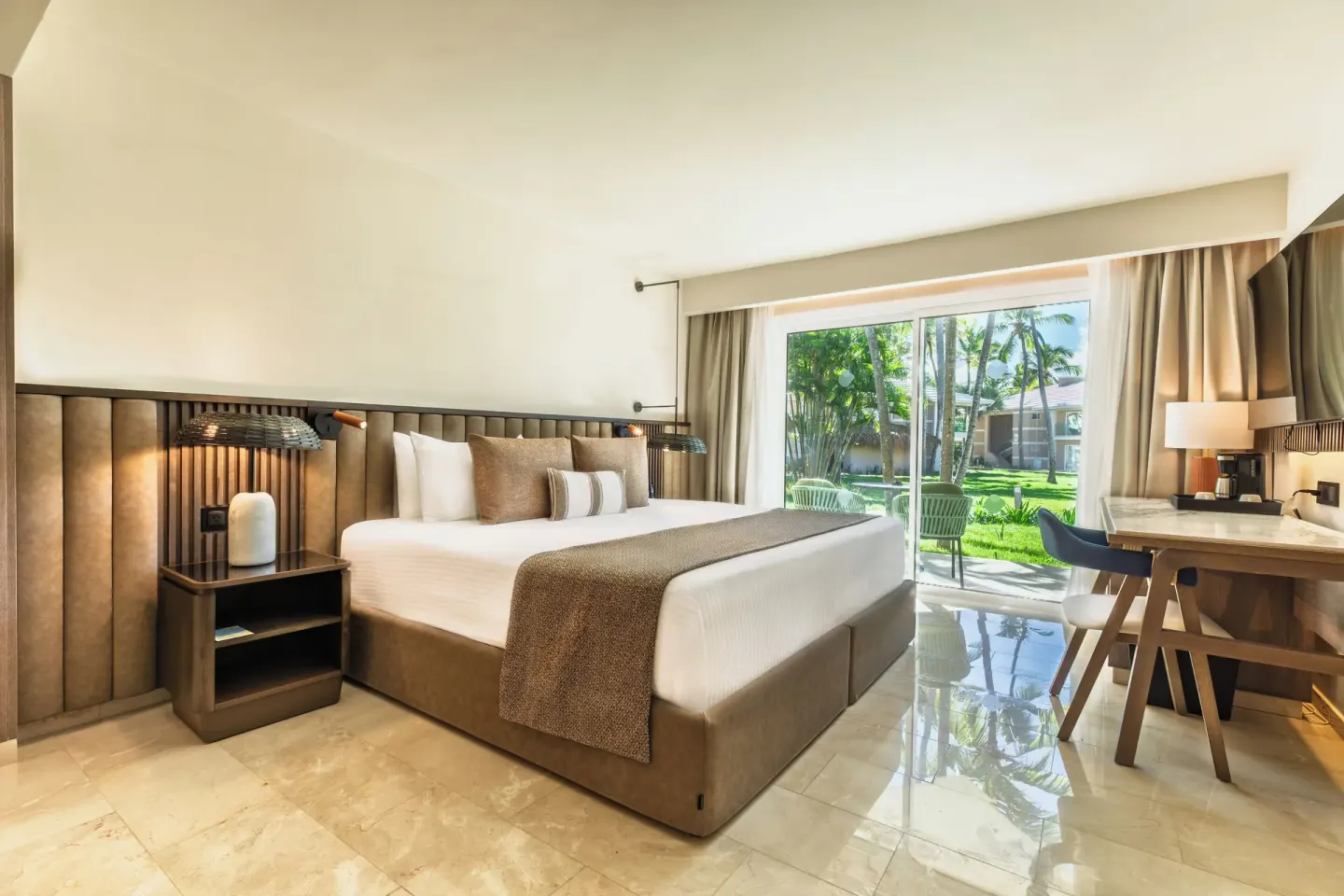 Romance Suite Garden View king bed with desk and patio at Grand Palladium Select Bávaro.