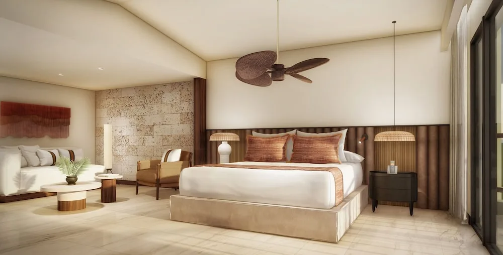 Junior Suite with king bed, sofa area, and balcony doors at Grand Palladium Select Bávaro.