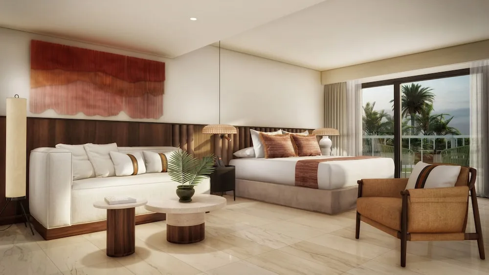Junior Suite with king bed, sofa, armchair, and balcony view at Grand Palladium Select Bávaro.