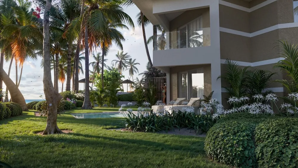 Garden-view suite exterior with terrace, palms, and lawn at Grand Palladium Select Bávaro.