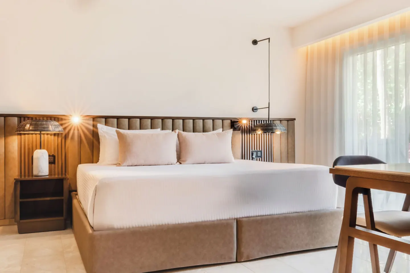 Superior Junior Suite Garden View king bed at Grand Palladium Select Bávaro with bedside lamps and sheer curtains.