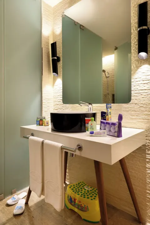 Bathroom vanity with black basin and child step stool at Grand Palladium Select Costa Mujeres.