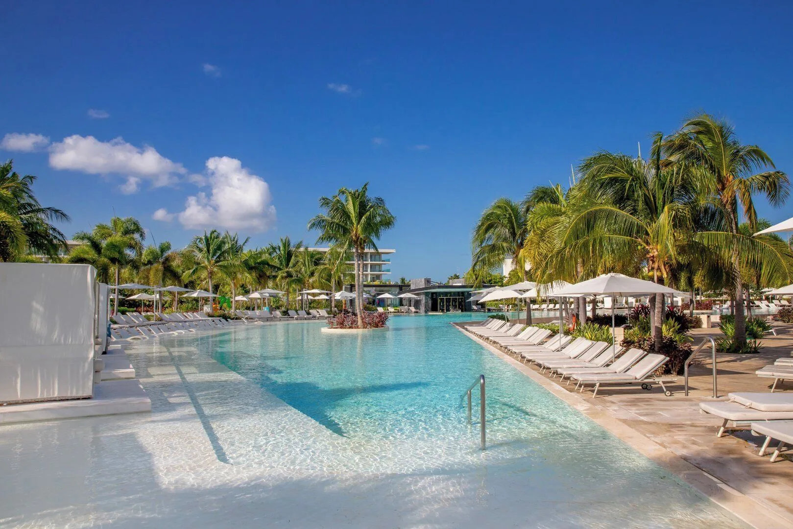 Long resort pool with steps, loungers, and palms at Grand Palladium Select Costa Mujeres.