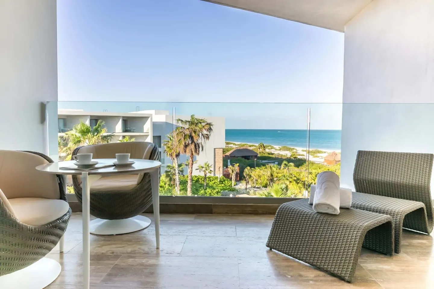 Ocean-view terrace with loungers and table at Grand Palladium Select Costa Mujeres.