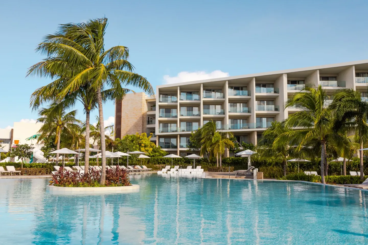 Pool, palms, umbrellas, and guest-room balconies at Grand Palladium Select Costa Mujeres.