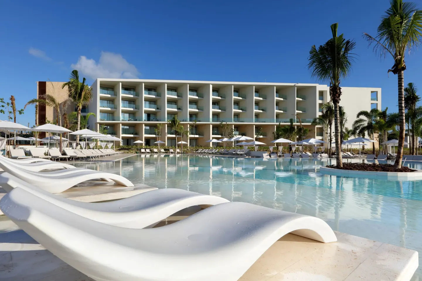 Curved white in-water loungers beside the pool at Grand Palladium Select Costa Mujeres.