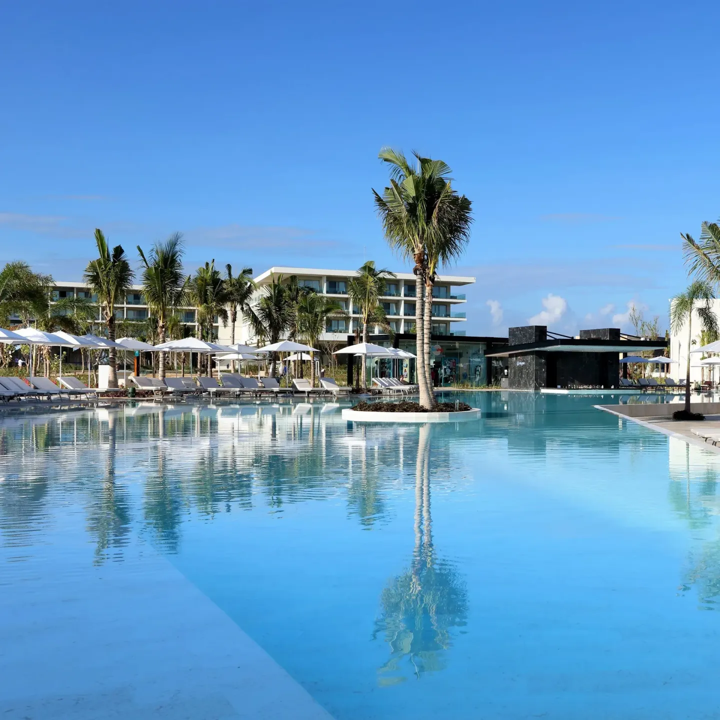 Large reflective pool with palms and a bar at Grand Palladium Select Costa Mujeres.