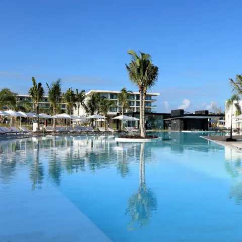 Large reflective pool with palms and a bar at Grand Palladium Select Costa Mujeres.