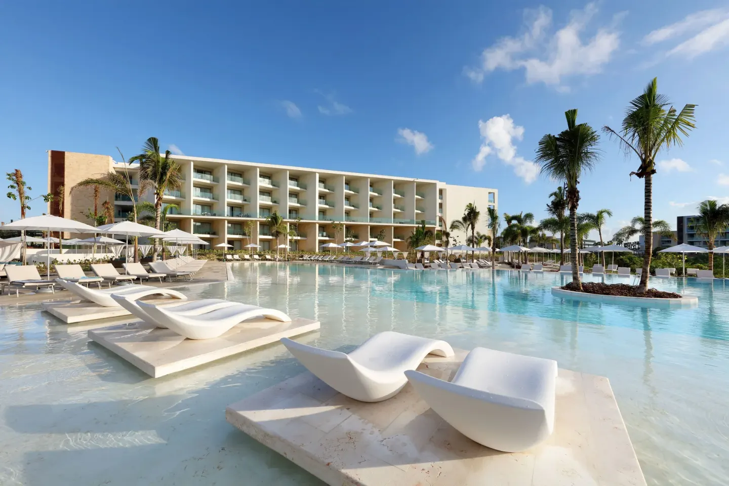 Large resort pool with in-water loungers at Grand Palladium Select Costa Mujeres.