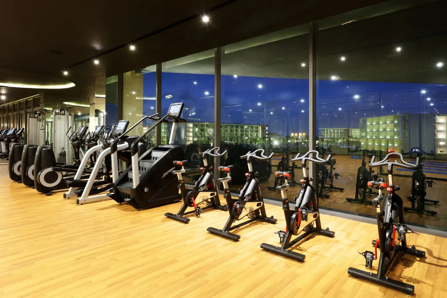 Spin bikes and treadmills face tall windows at Grand Palladium Select Costa Mujeres.