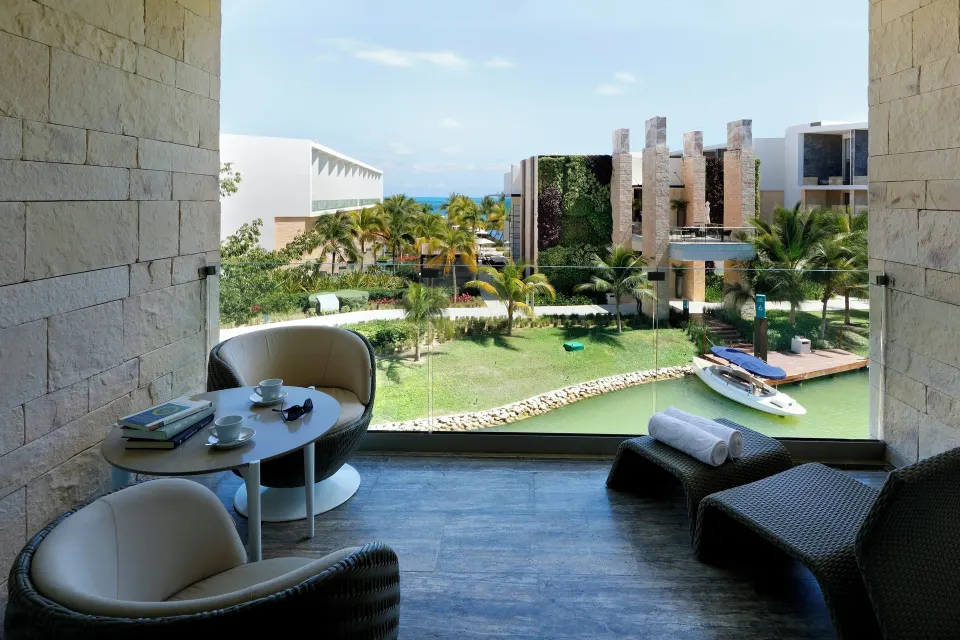 Junior Suite balcony with seating, loungers, lagoon, and resort views at Grand Palladium Select Costa Mujeres.