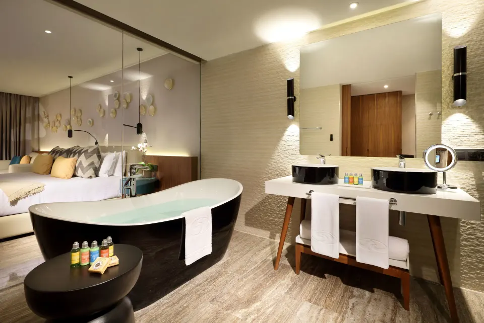 Junior Suite bathroom with tub and king bed at Grand Palladium Select Costa Mujeres.