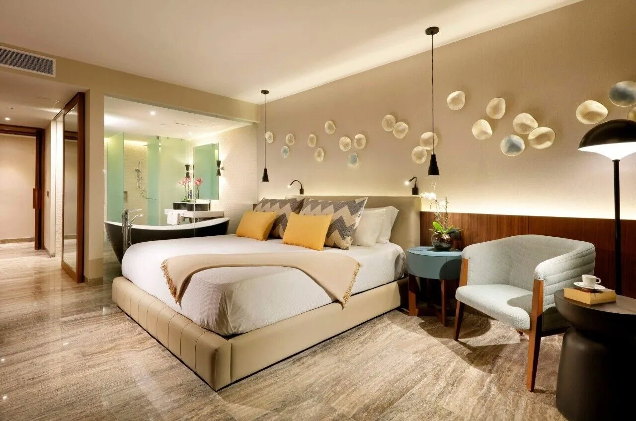 Junior Suite with king bed, chair, and open bath at Grand Palladium Select Costa Mujeres.