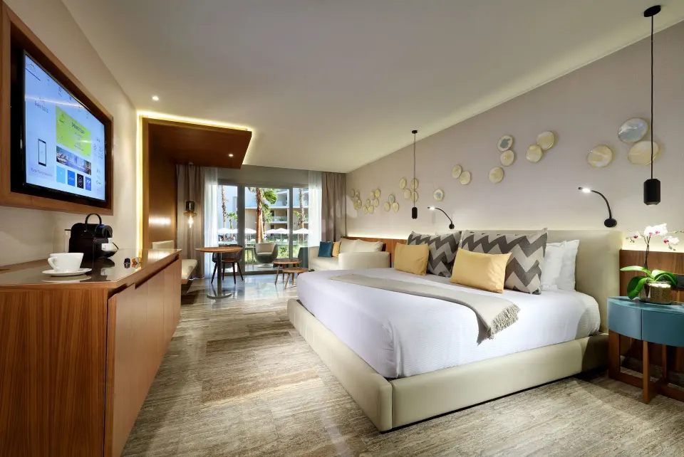 Junior Suite with king bed, TV, refreshment area, and patio doors at Grand Palladium Select Costa Mujeres.