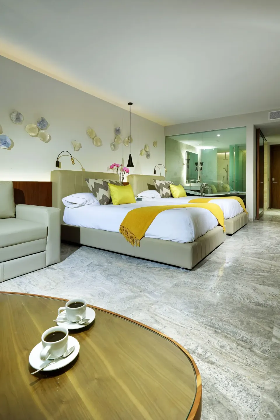 Junior Suite with two beds, coffee table, and glass bath area at Grand Palladium Select Costa Mujeres.