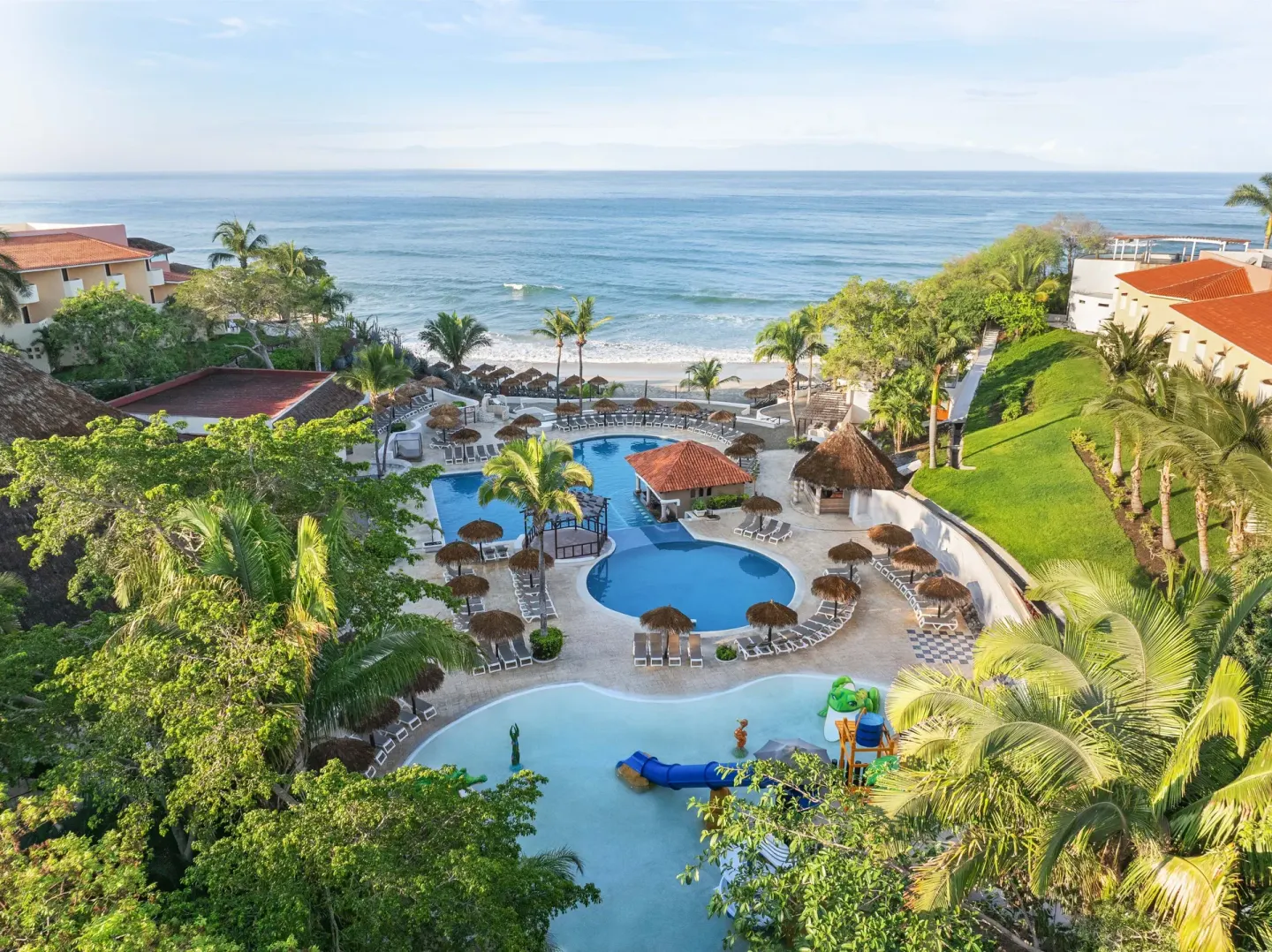 Aerial view of pools, palms, and beach at Grand Palladium Vallarta Resort & Spa.