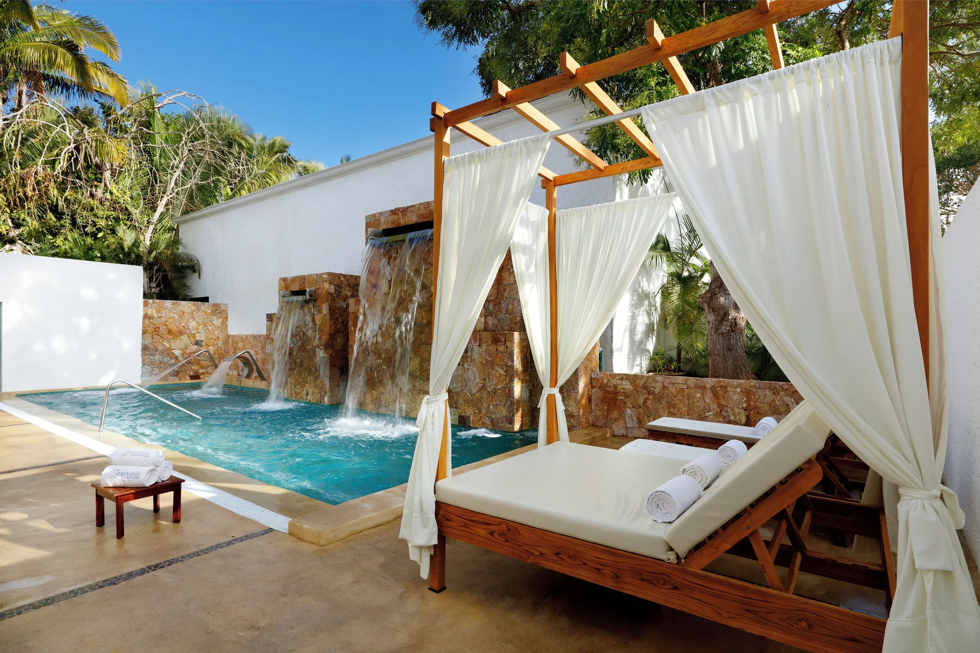 Canopied spa lounger beside a waterfall pool at Grand Palladium Vallarta Resort & Spa.