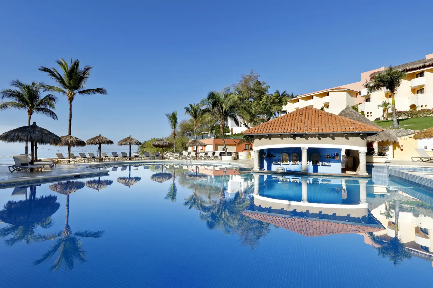 Main pool with swim-up bar and palm reflections at Grand Palladium Vallarta Resort & Spa.