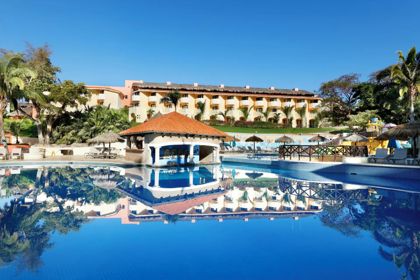 Main pool with swim-up pavilion and reflected resort buildings at Grand Palladium Vallarta Resort & Spa.