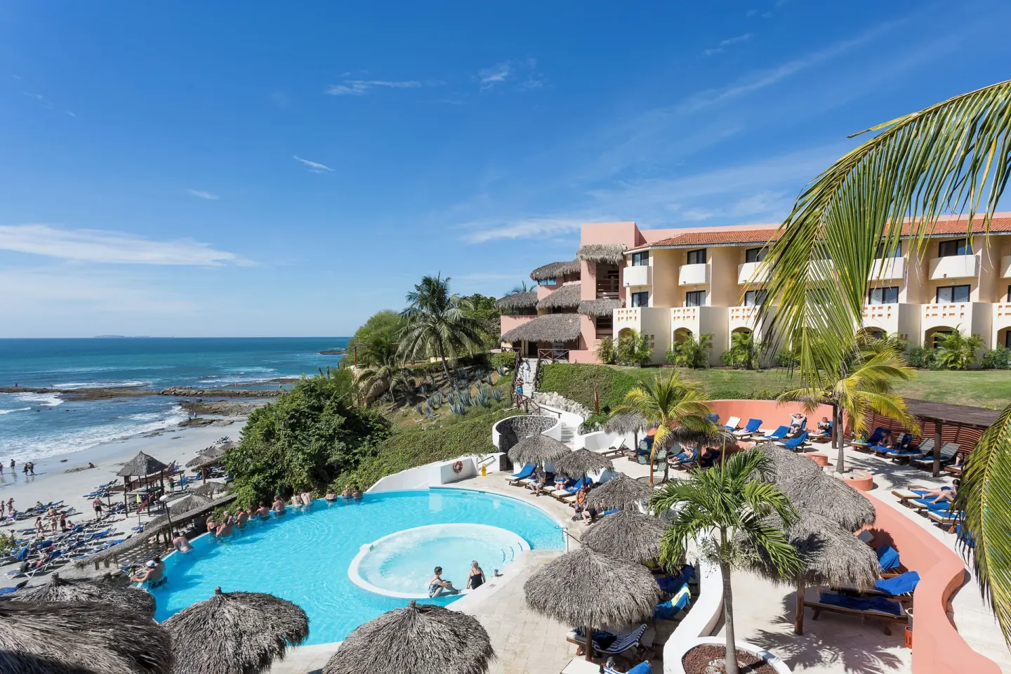 Oceanfront pool and beach with loungers at Grand Palladium Vallarta Resort & Spa.