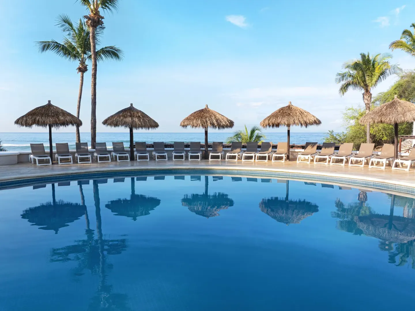 Oceanfront pool with palapas at Grand Palladium Vallarta Resort & Spa.