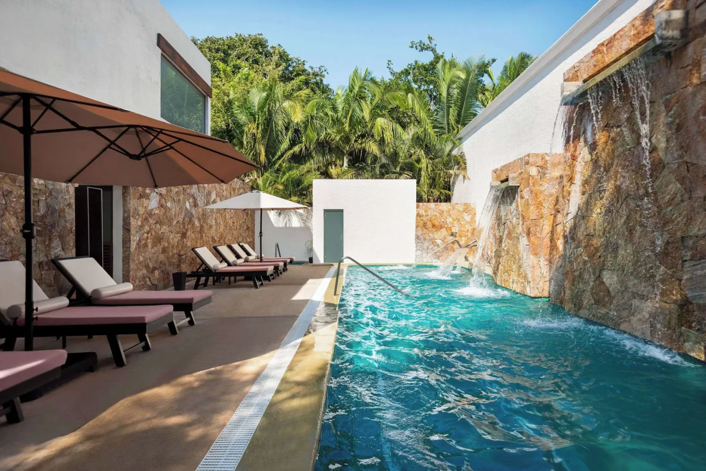 Outdoor spa pool with waterfalls, umbrellas, and loungers at Grand Palladium Vallarta Resort & Spa.