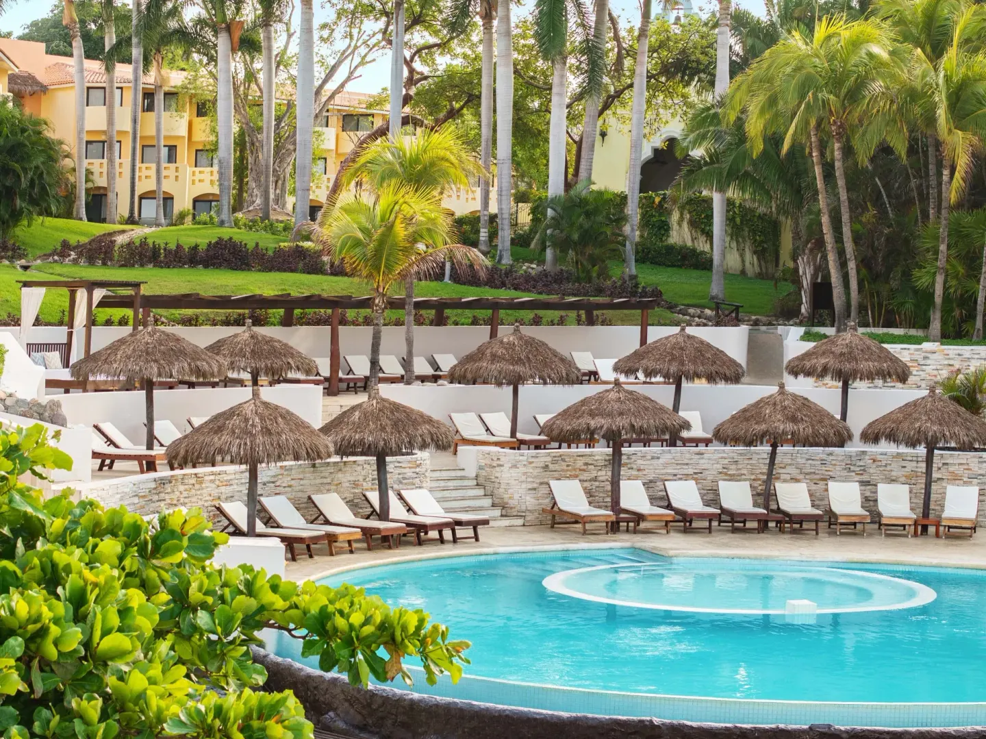 Pool terraces with palapa umbrellas and loungers at Grand Palladium Vallarta Resort & Spa.