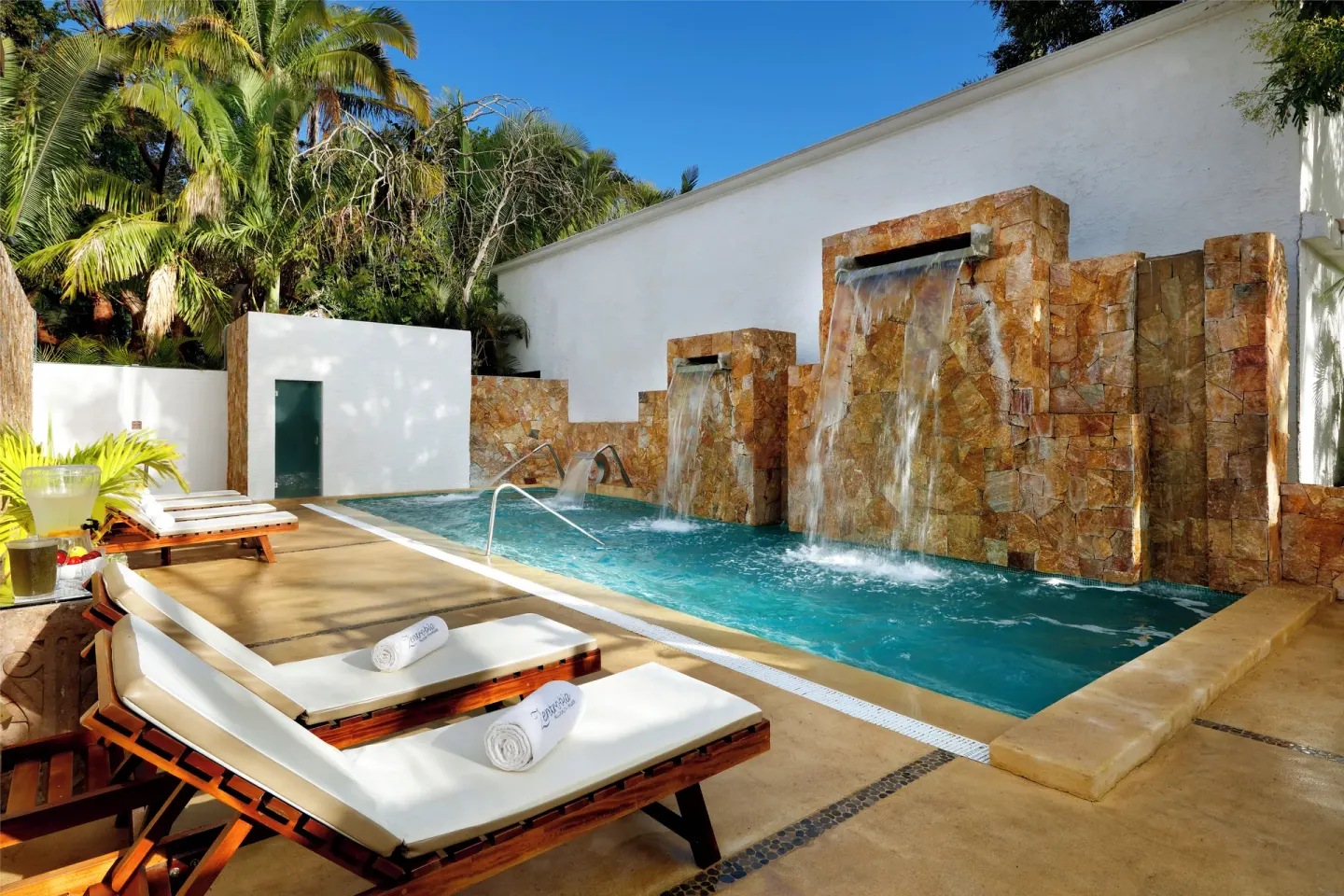 Spa plunge pool with stone waterfalls and lounge chairs at Grand Palladium Vallarta Resort & Spa.