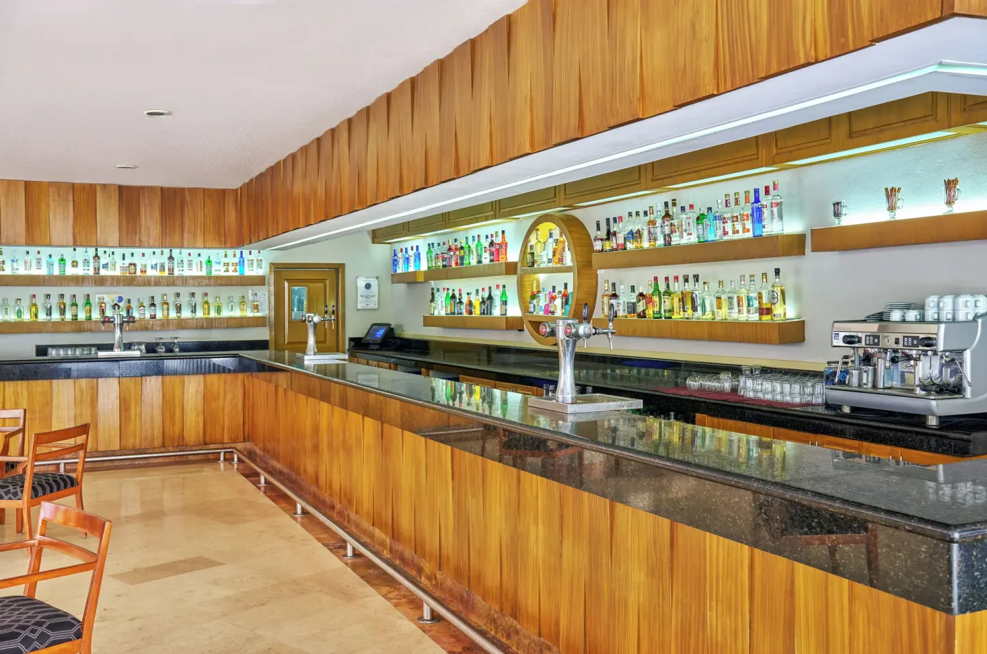Long wooden bar with backlit bottles at Grand Palladium Vallarta Resort & Spa.