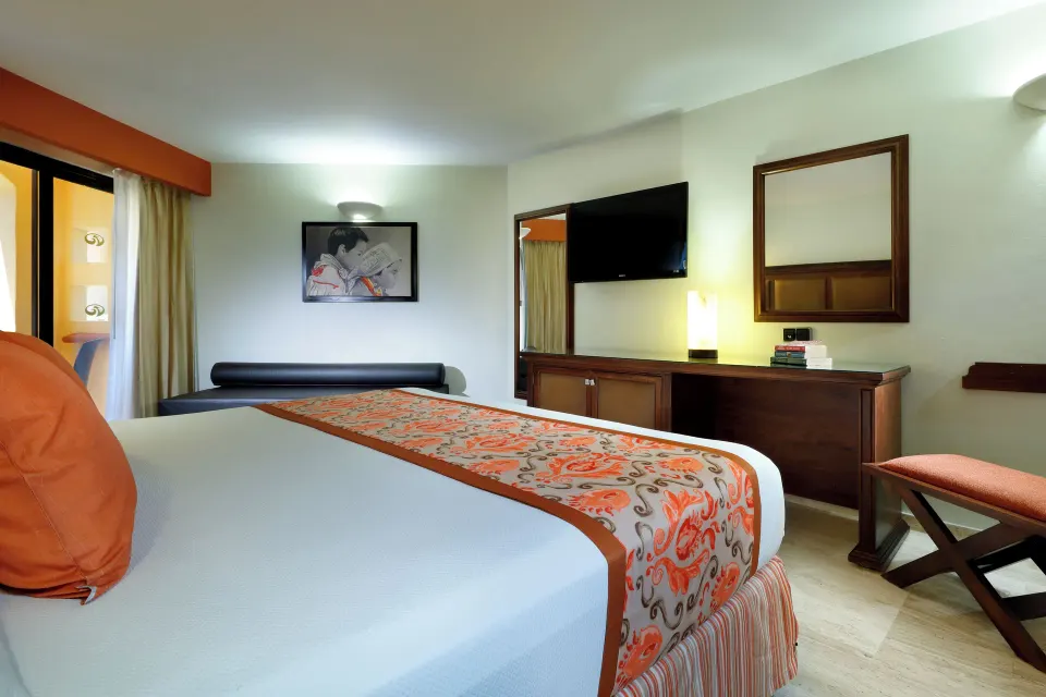 Deluxe Room king bed facing the TV and dresser at Grand Palladium Vallarta Resort & Spa.