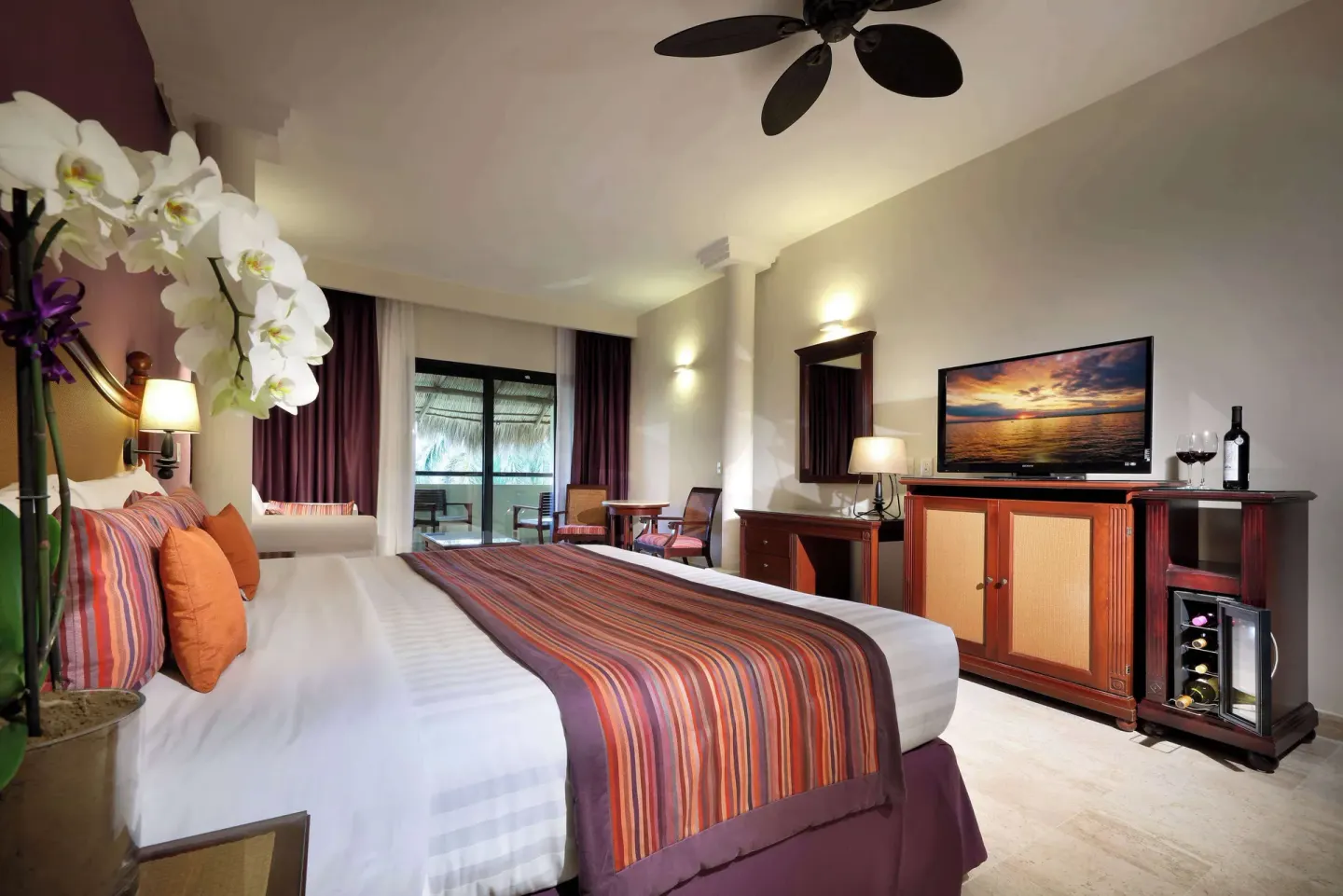 Family Selection Junior Suite bed, television and minibar at Grand Palladium Vallarta Resort & Spa.