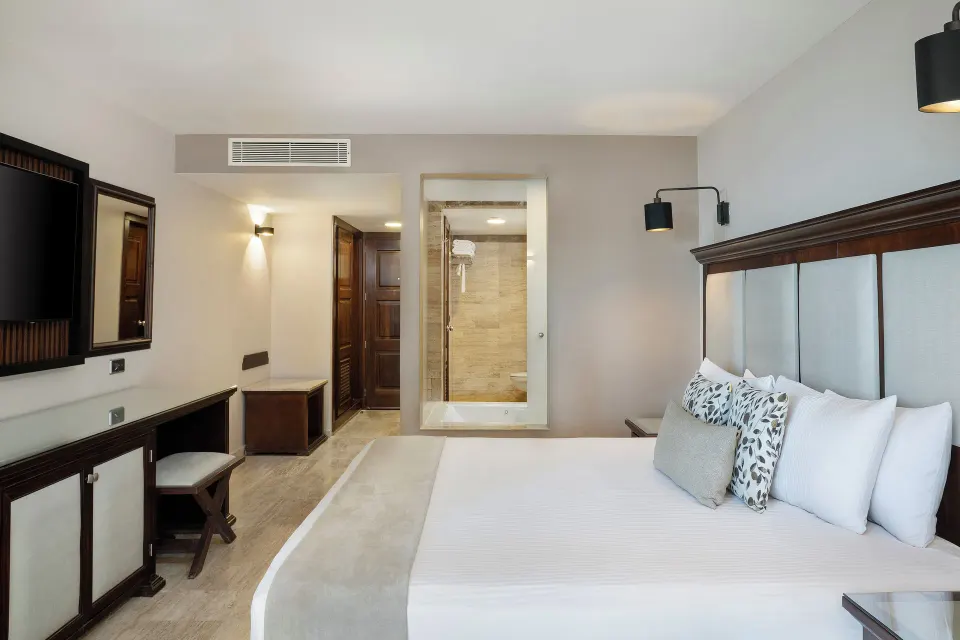 Junior Suite king bed facing bathroom and TV at Grand Palladium Vallarta Resort & Spa.