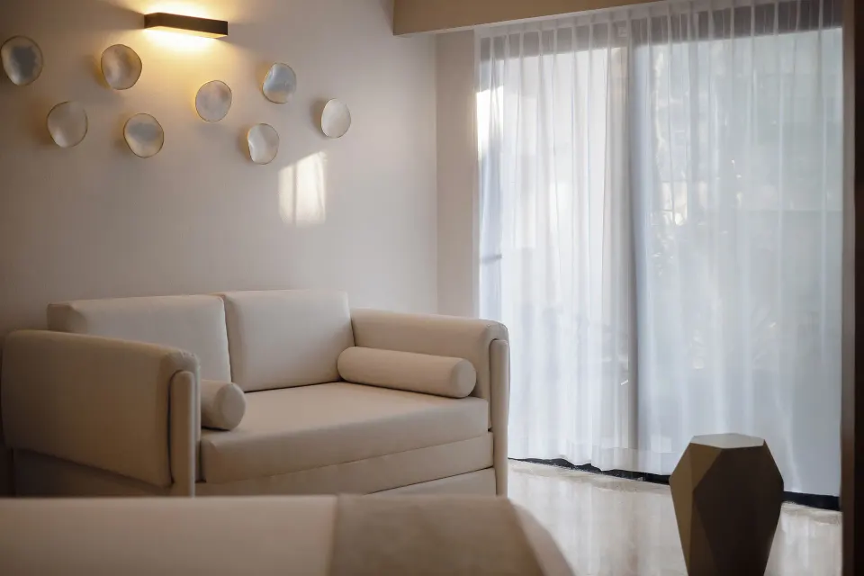 Junior Suite sofa by sheer-curtained terrace doors at Grand Palladium Vallarta Resort & Spa.