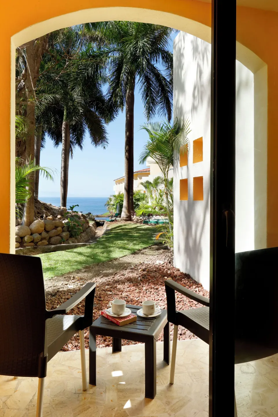 Junior Suite terrace with chairs and ocean glimpses at Grand Palladium Vallarta Resort & Spa.