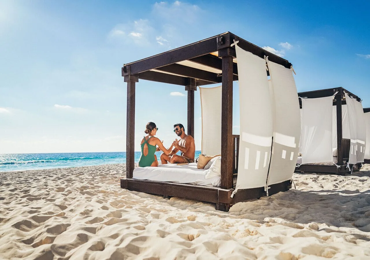 Couple sits on a beach cabana facing the ocean at Grand Park Royal Cancun.