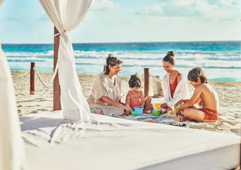 Family plays with beach toys beside a cabana at Grand Park Royal Cancun.