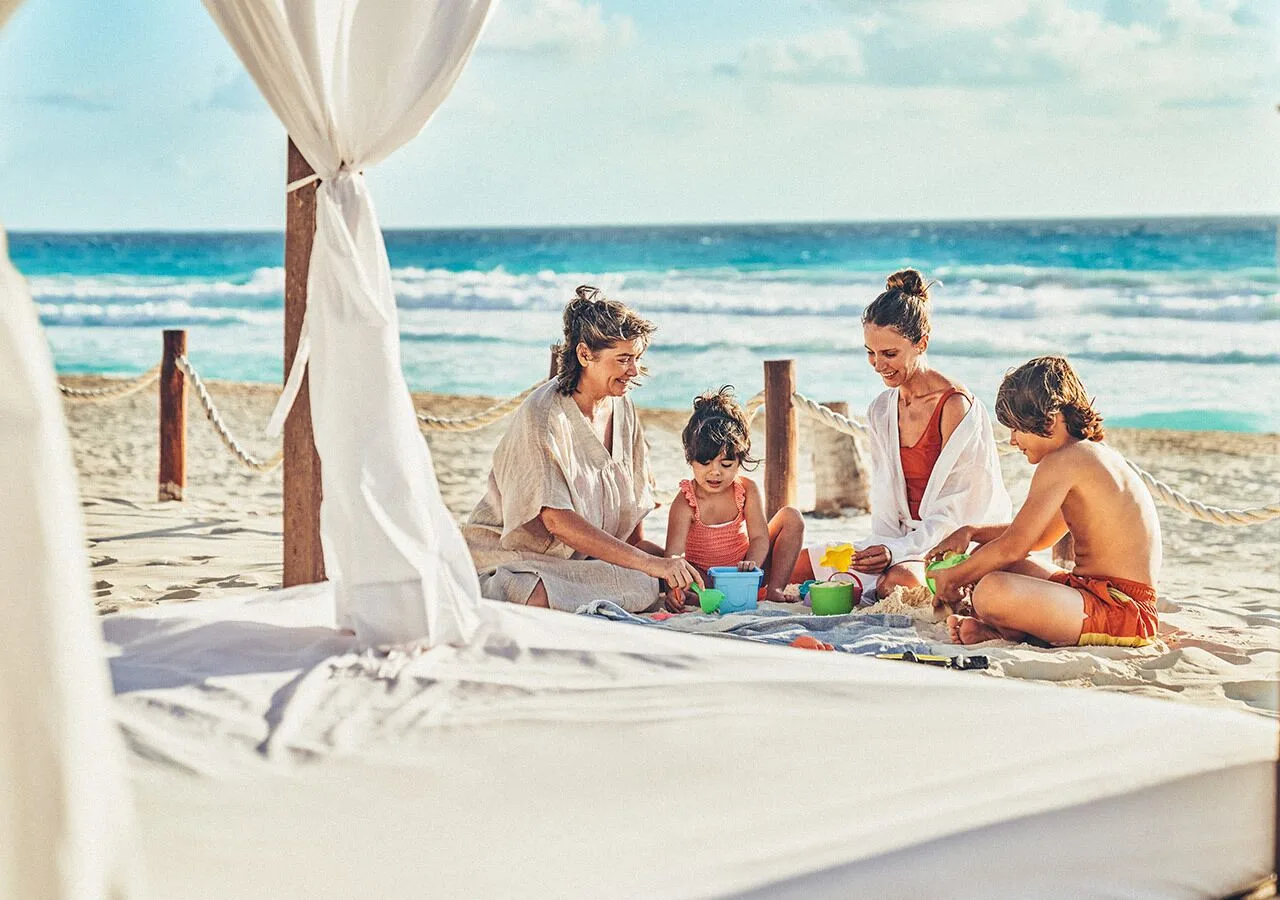 Family plays with beach toys beside a cabana at Grand Park Royal Cancun.